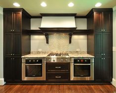 an empty kitchen with wood floors and stainless steel stove top ovens, cabinets, and counter tops