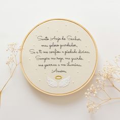 a white embroidered hoop with a poem written on it next to some flowers and leaves