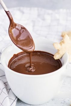 a spoon pouring chocolate into a white bowl