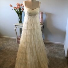 a wedding dress is displayed on a mannequin next to a vase with flowers