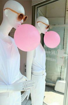 two mannequins wearing sunglasses and holding pink balloons