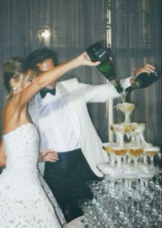 a bride and groom are standing in front of a cake with champagne being poured on it