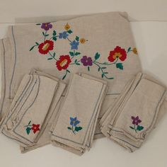 four pieces of embroidered linen with flowers on them, all in different colors and sizes