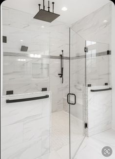 a walk in shower sitting next to a white counter top and tiled walls with black accents