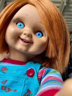 a close up of a doll with red hair and blue eyes, wearing overalls