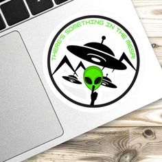 an alien sticker sitting on top of a laptop