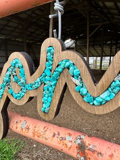 a wooden sign with turquoise beads hanging from it's side