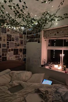 an unmade bed in a bedroom with lots of pictures on the wall and lights hanging from the ceiling