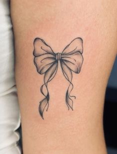 a woman's thigh with a bow tattoo on her left side ribcage