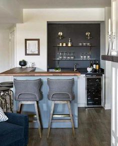 a kitchen with two bar stools next to an open living room and dining area