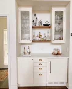 a kitchen with white cabinets and gold pulls on the cupboards is seen in this image