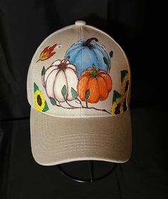 a baseball cap with pumpkins and leaves on it, sitting on a black background