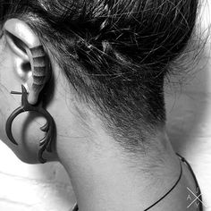 the back of a woman's head with ear piercings in black and white