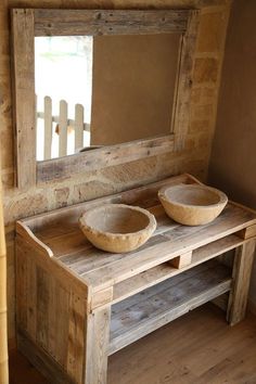 a wooden table with two bowls on it and a mirror in the corner next to it