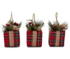 three red and black plaid wrapped presents with pine branches