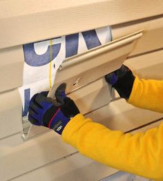 a woman in yellow jacket working on window sill with blue and white banner behind her