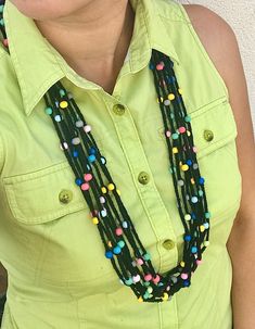 a woman wearing a green shirt with multi colored beads