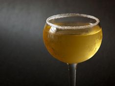 a glass filled with liquid on top of a table next to a black wall and floor