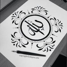 an arabic calligraphy logo is displayed on a piece of paper with a pen next to it