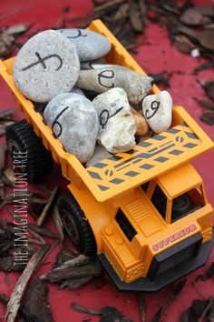 a yellow toy truck with rocks in the back and writing on it's side