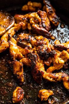 chicken is cooking in a skillet with sauce on the side, and it looks to be fried