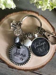 a personalized keychain is sitting on top of a piece of wood with flowers in the background