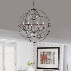 a chandelier hanging from the ceiling in a dining room with white walls and patterned flooring