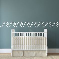 a baby's room with a crib and wall decal in the shape of waves