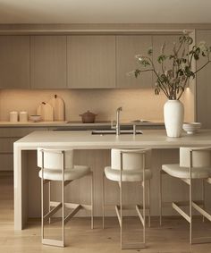 a kitchen island with three stools next to it and a potted plant on the counter