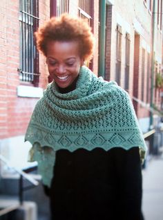 a woman smiles as she walks down the street with her shawl draped over her shoulders