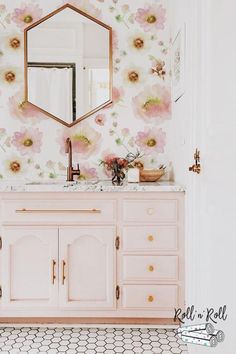 a bathroom with white walls and pink vanity, gold mirror above the sink, and hexagonal tile flooring