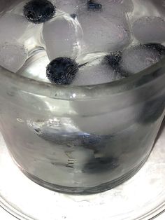 a glass filled with ice and blueberries on top of a table