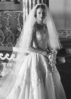 an old black and white photo of a woman wearing a wedding dress with long veil