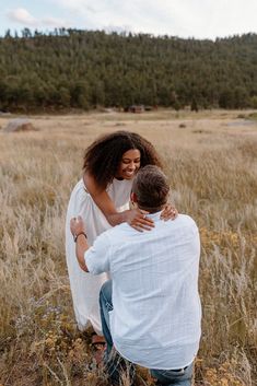 a man kneeling down next to a woman in a field