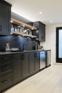 a kitchen with black cabinets and wooden floors