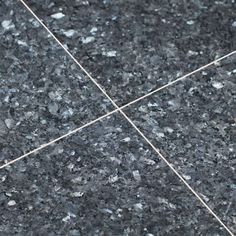 a close up view of a black marble floor with white lines in the middle and grey speckles on it