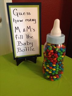 a bottle filled with candy next to a sign that says guess how many m & m's fill the baby bottle