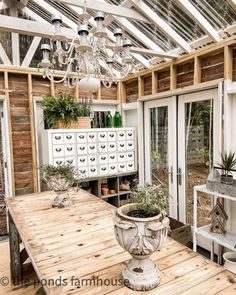 a wooden table sitting inside of a greenhouse filled with lots of plants and potted plants