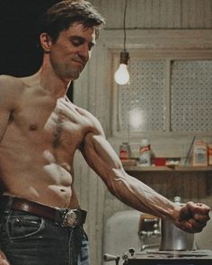 a shirtless man standing in a kitchen next to a stove