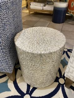 a white and blue stool sitting on top of a rug next to a chair in a store