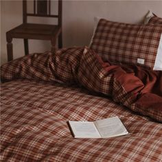 an open book laying on top of a bed next to a pillow and blanket in a bedroom