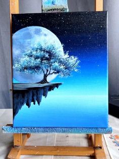 an easel with a painting on it that has a tree and moon in the sky