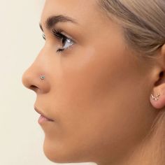 a woman with ear piercings on her nose looking off to the side, in profile