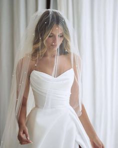 a woman in a white wedding dress wearing a veil