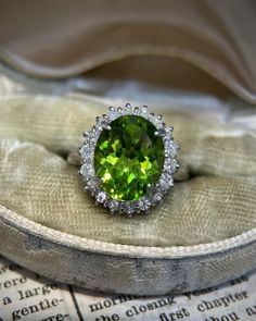 an oval cut peridot and diamond ring sits on top of a cloth bag