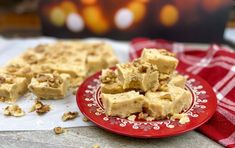 a red plate topped with pieces of fudge next to a pile of walnuts