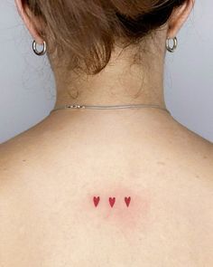 the back of a woman's neck with three small hearts on it