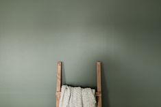 a towel rack with two towels hanging on it's side against a green wall