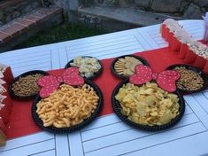 three mickey mouse plates filled with cereal and crackers on a red tablecloth covered picnic table