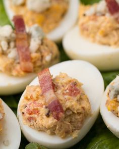 deviled eggs with bacon and cheese are on a bed of lettuce leaves